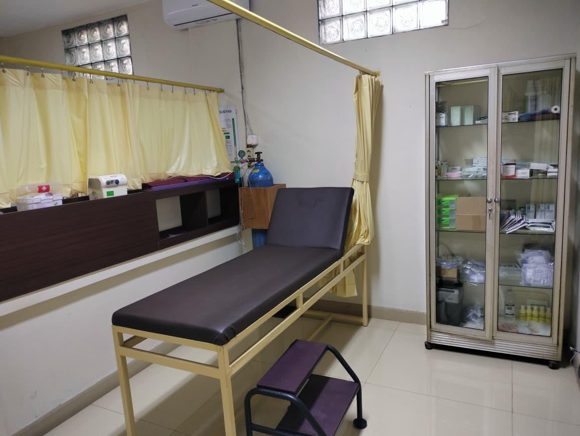 Ruang EKG dengan tempat tidur periksa, tirai, dan lemari alat