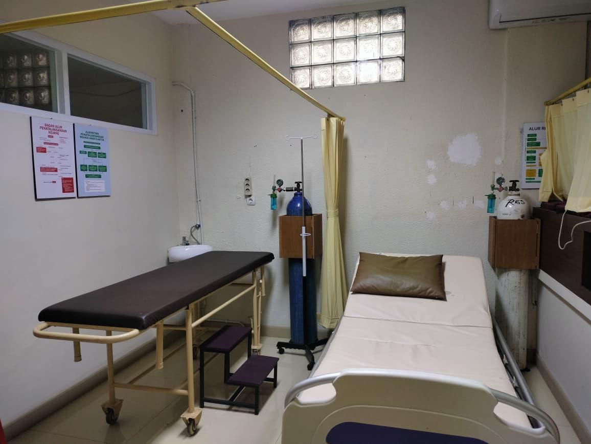 Ruang tindakan dengan dua tempat tidur, tiang infus, dan tabung oksigen